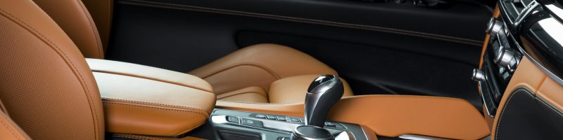 Modern luxury car Interior - steering wheel, shift lever and dashboard. Car interior luxury. Beige comfortable seats, steering wheel, dashboard, speedometer, display. Orange perforated leather.